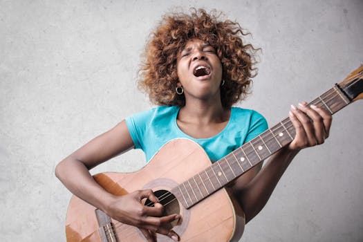 A young woman passionately sings while playing an acoustic guitar indoors.