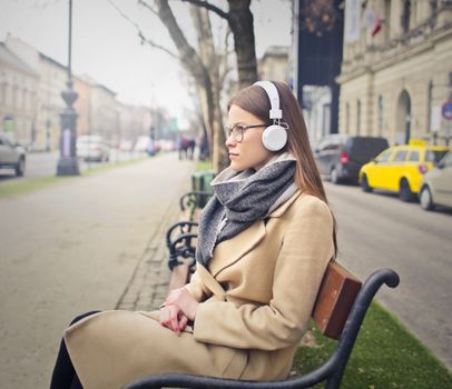 Woman Sitting On Black and Brown Bench Listening to Music