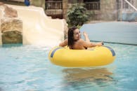 在一个阳光明媚的日子，一位微笑的女人在游泳池里，坐在黄色的浮垫上