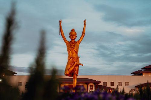 Free A golden statue set against a dramatic cloudy sky, photographed outdoors. Stock Photo