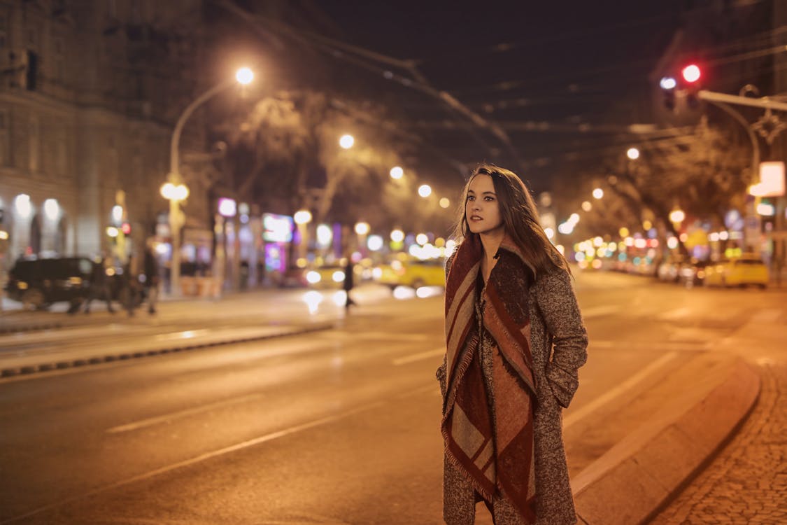 Woman Walking on Sidewalk Near Asphalt Road