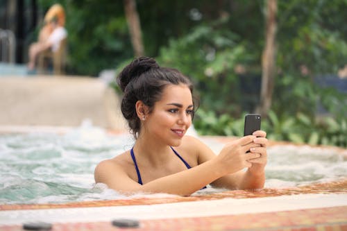 Photo of a Woman in Jacuzzi Using Smartphone