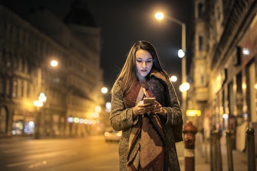 Frau, Die Auf Bürgersteig Hält, Der Smartphone Hält