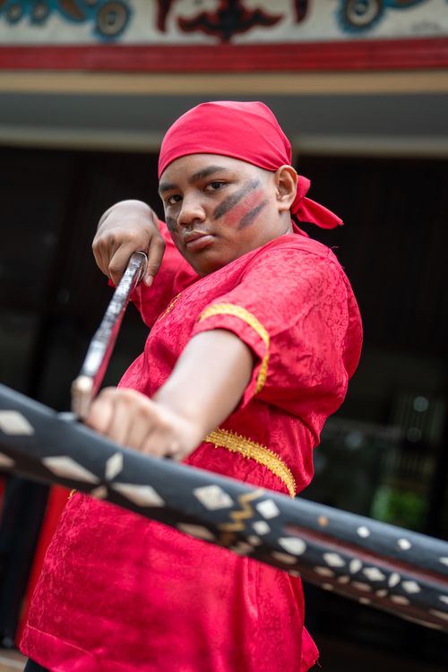 Free Confident young performer in vibrant red traditional clothing with a sword. Stock Photo