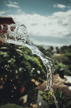 A Man Pouring A Glass of Water Under Cloudy Sky