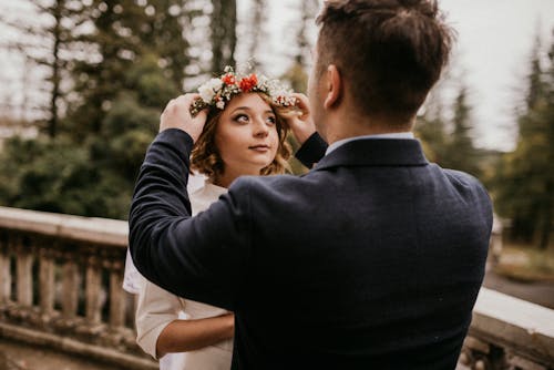 Uomo In Vestito Nero Che Mette Il Fiore Della Corona Sulla Testa Della Donna