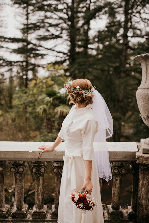 Woman in White Dress Standing on Concrete Fence