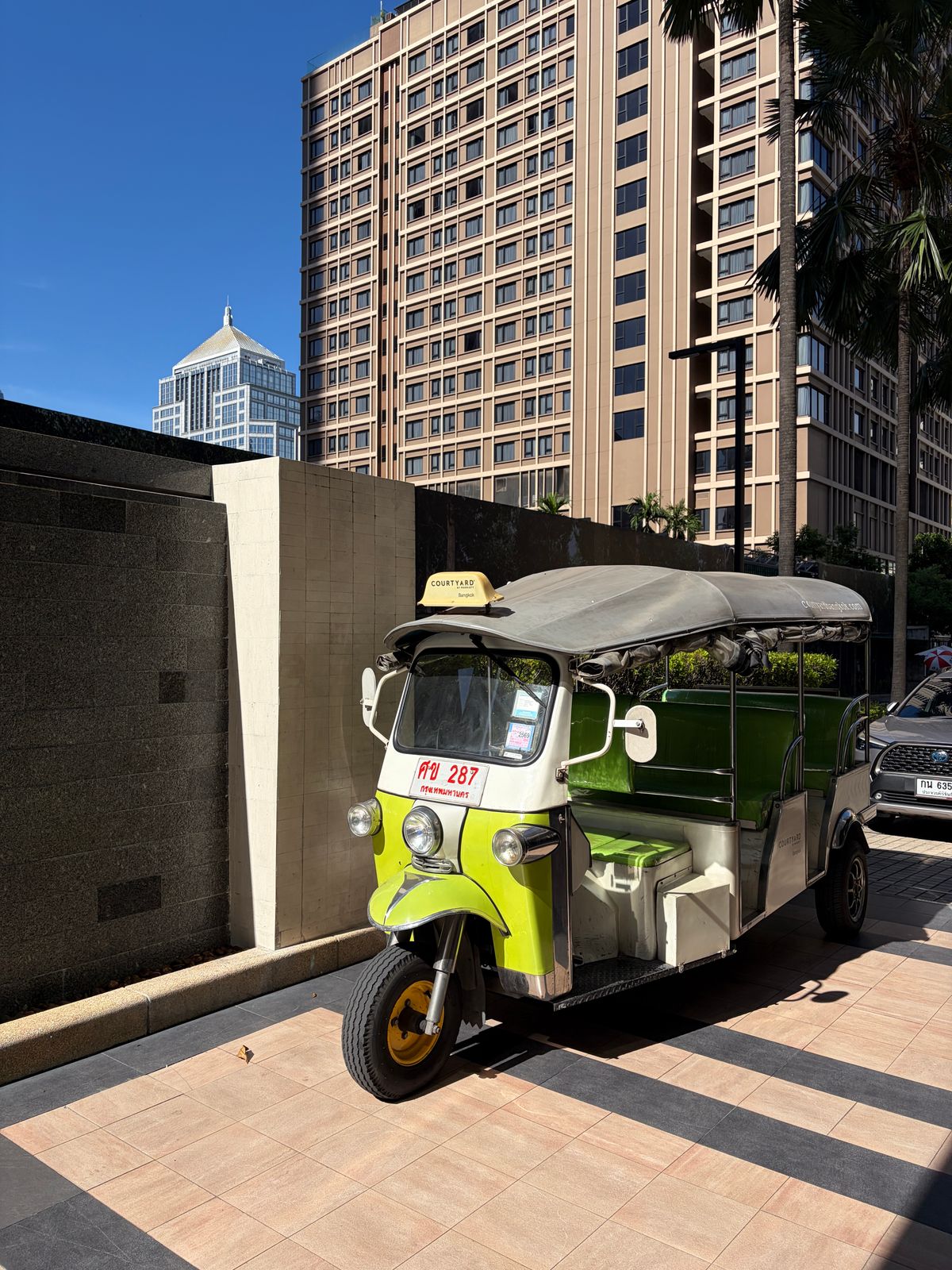 Unde te cazezi în Bangkok - Sukhumvit - tuk-tuk verde în fața zgârie-norilor