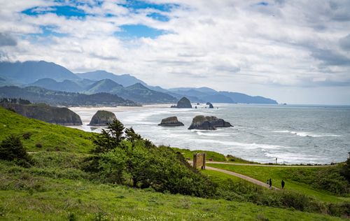 Free Picturesque landscape of Cannon Beach with Haystack Rock, lush greenery, and ocean waves. Stock Photo