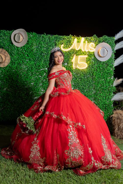 Free Elegant quinceañera in a red gown poses with a tiara under neon lights, celebrating her 15th birthday. Stock Photo
