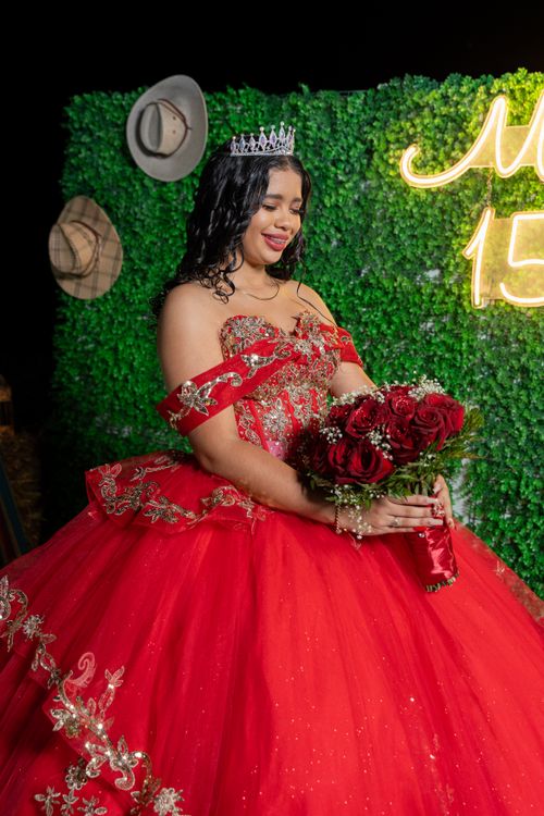 Free A young woman in a red gown celebrating her quinceañera with roses and tiara. Stock Photo
