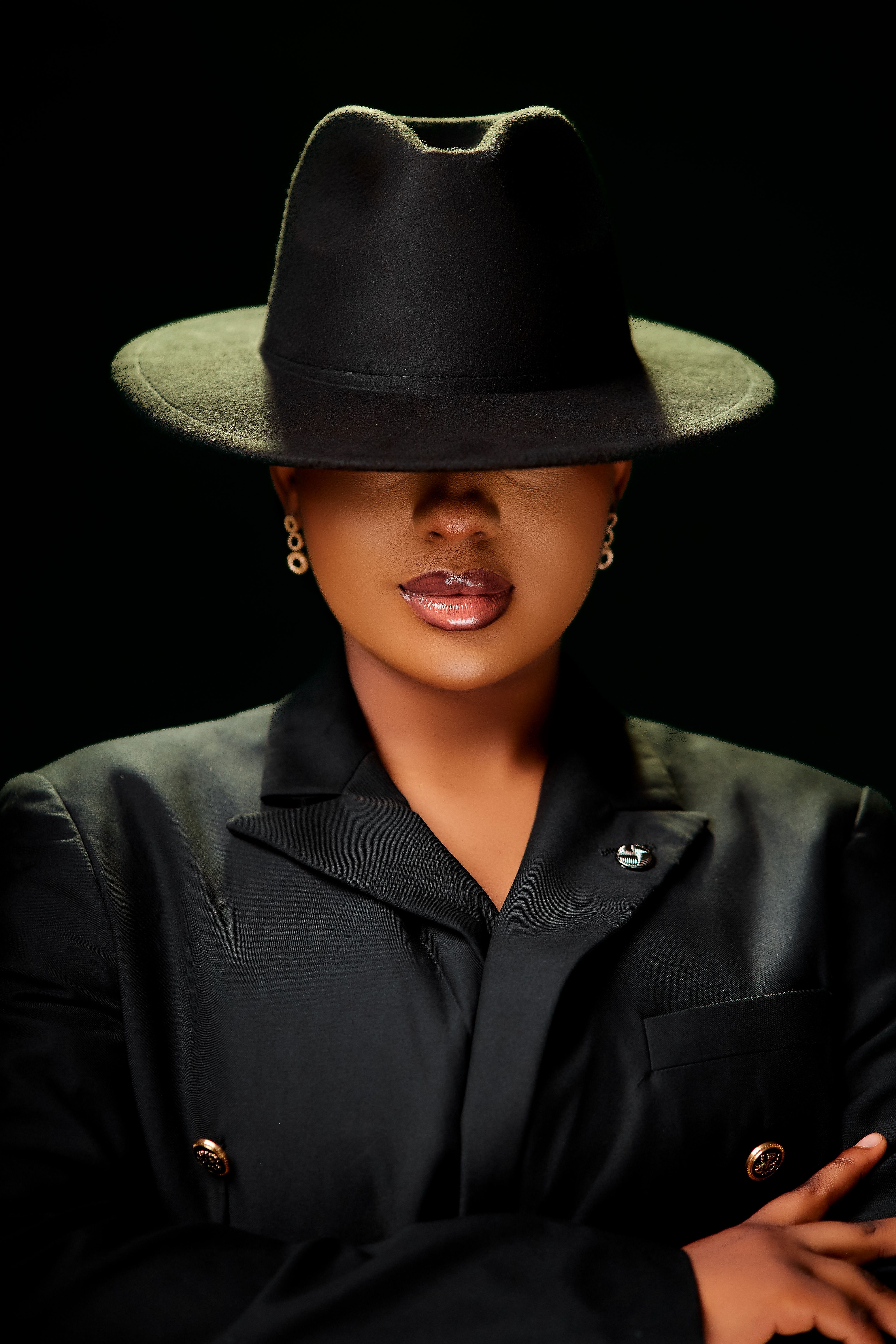 Stylish portrait of a woman in a black suit and hat, exuding sophistication.