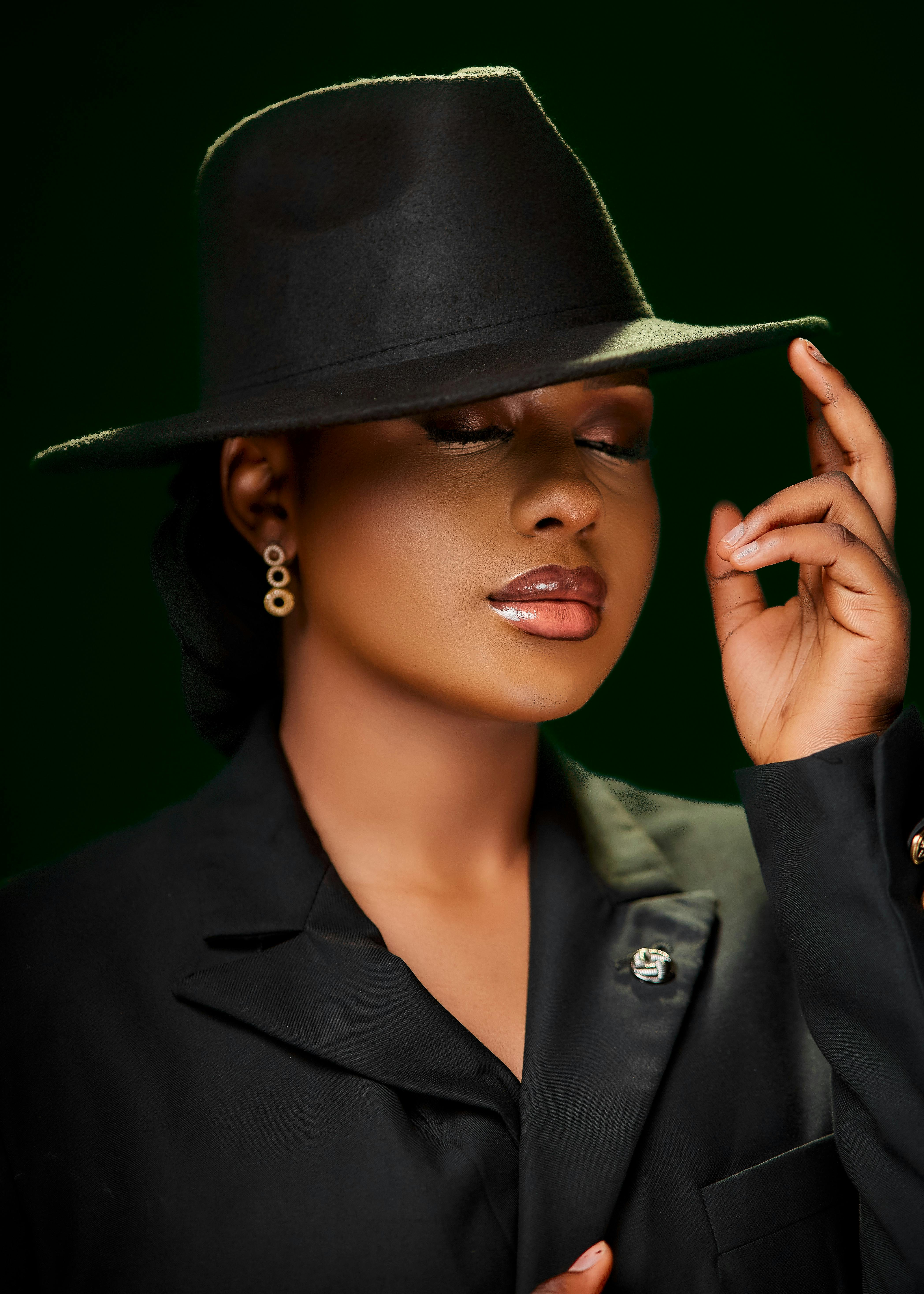 Stylish portrait of a woman in black hat and suit, eyes closed, graceful pose.
