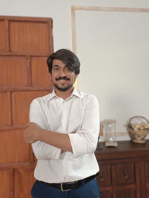 Free Confident man in a white shirt smiling indoors, standing with arms crossed. Stock Photo