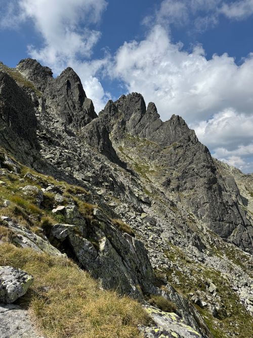 Free Majestic rocky peaks with grassy patches under a bright summer sky, showcasing natural beauty. Stock Photo