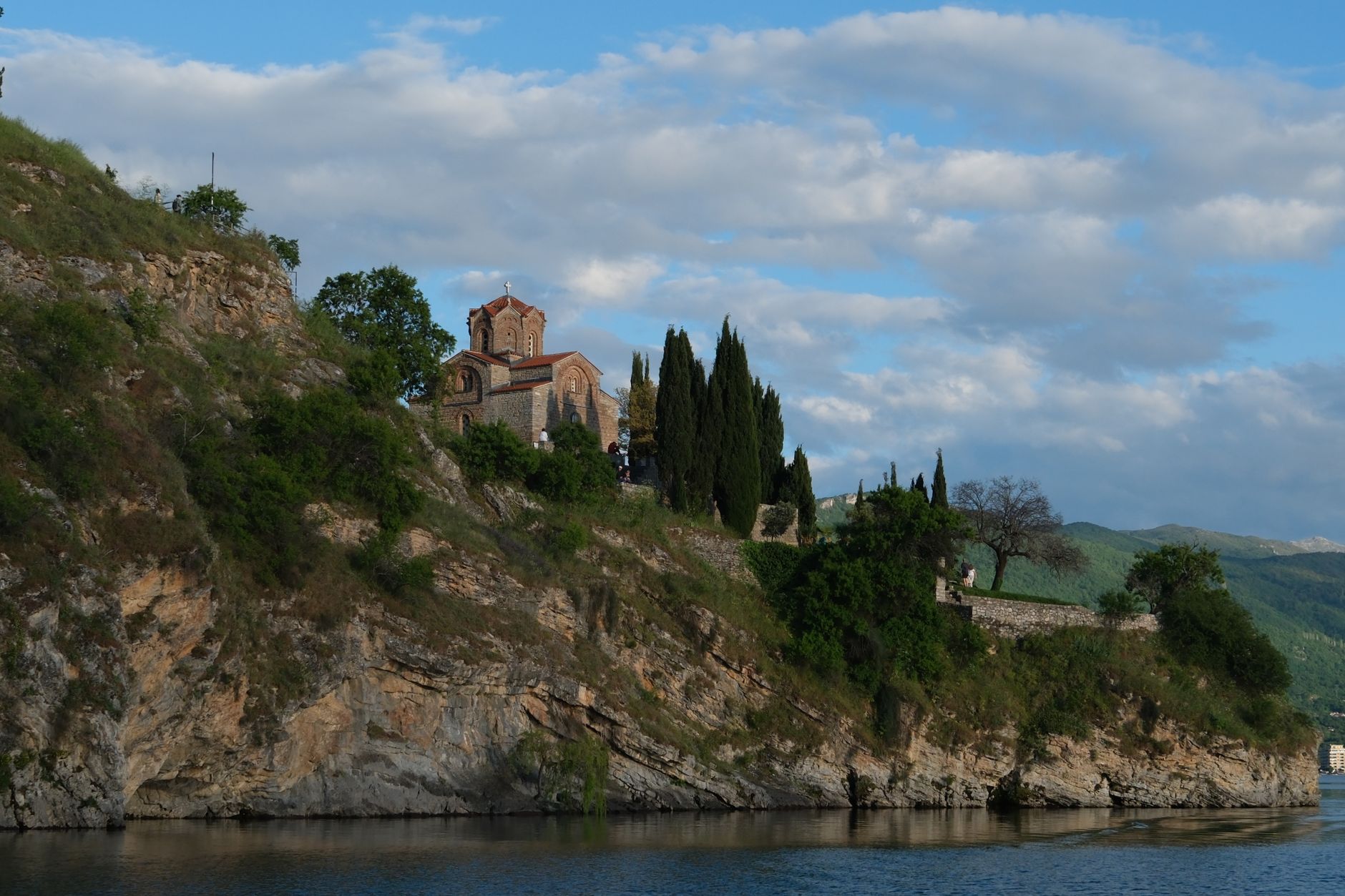 Scenic view of a historic church perched on a cliff overlooking Lake Ohrid against a blue sky. — photo by Seda Ünver / Pexels