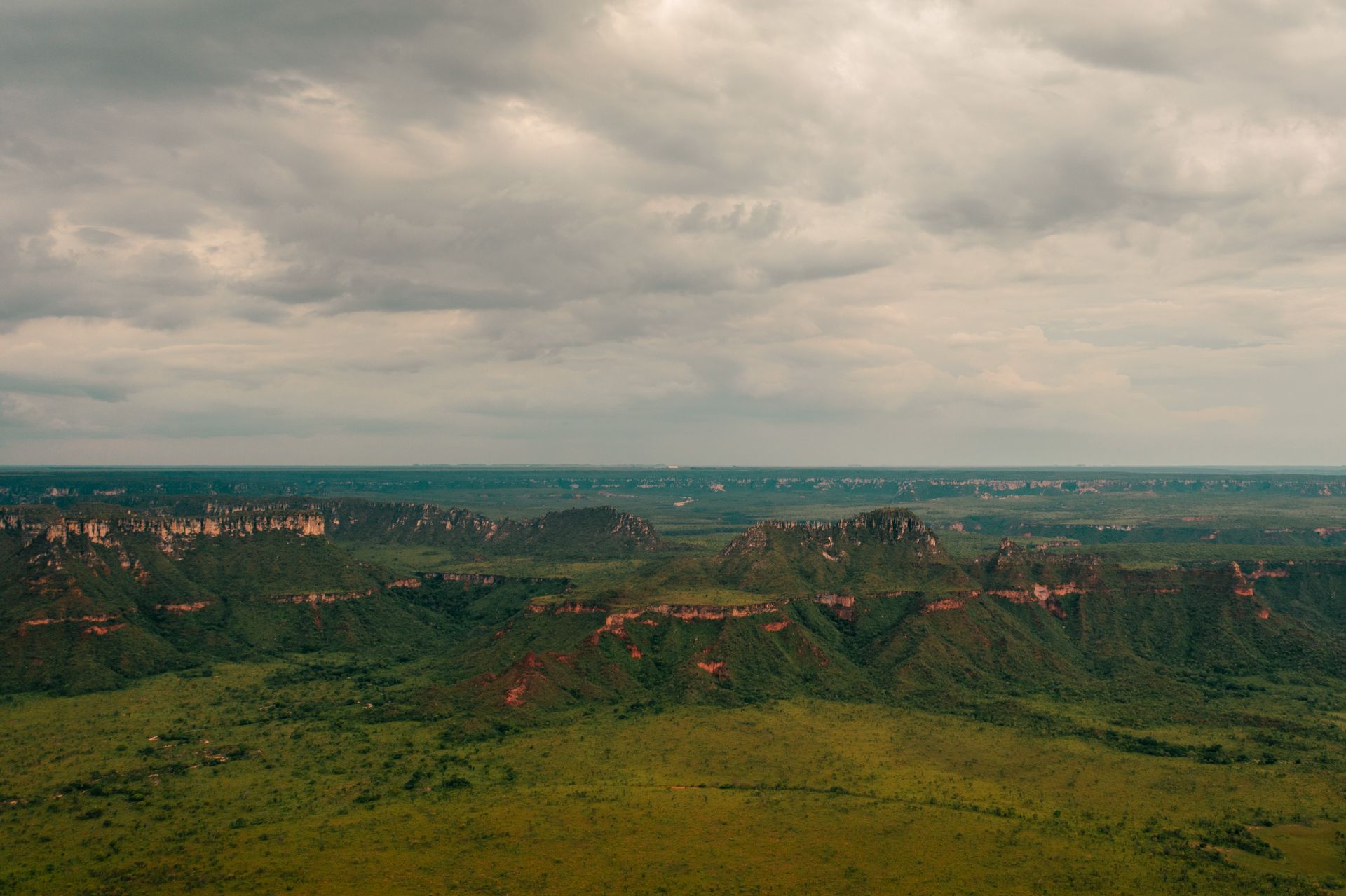 Stunning aerial shot of Serras Gerais' lush landscape in Tocantins, Brazil, featuring expansive green plains and rugged cliffs.
