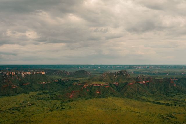 Stunning aerial shot of Serras Gerais' lush landscape in Tocantins, Brazil, featuring expansive green plains and rugged cliffs.