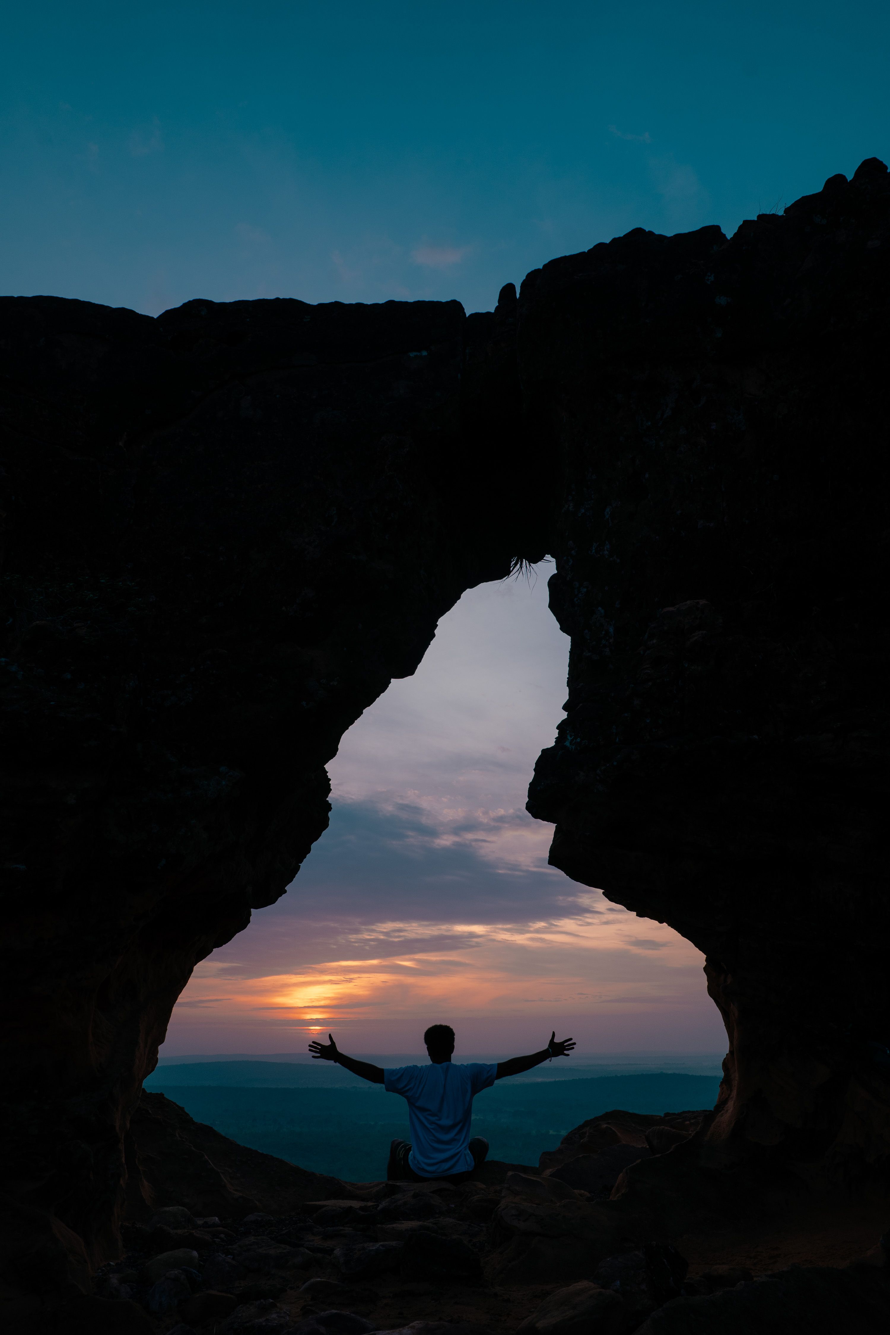 Silhouette of a person meditating in a rustic cave during sunrise in Maranhão, Brazil.