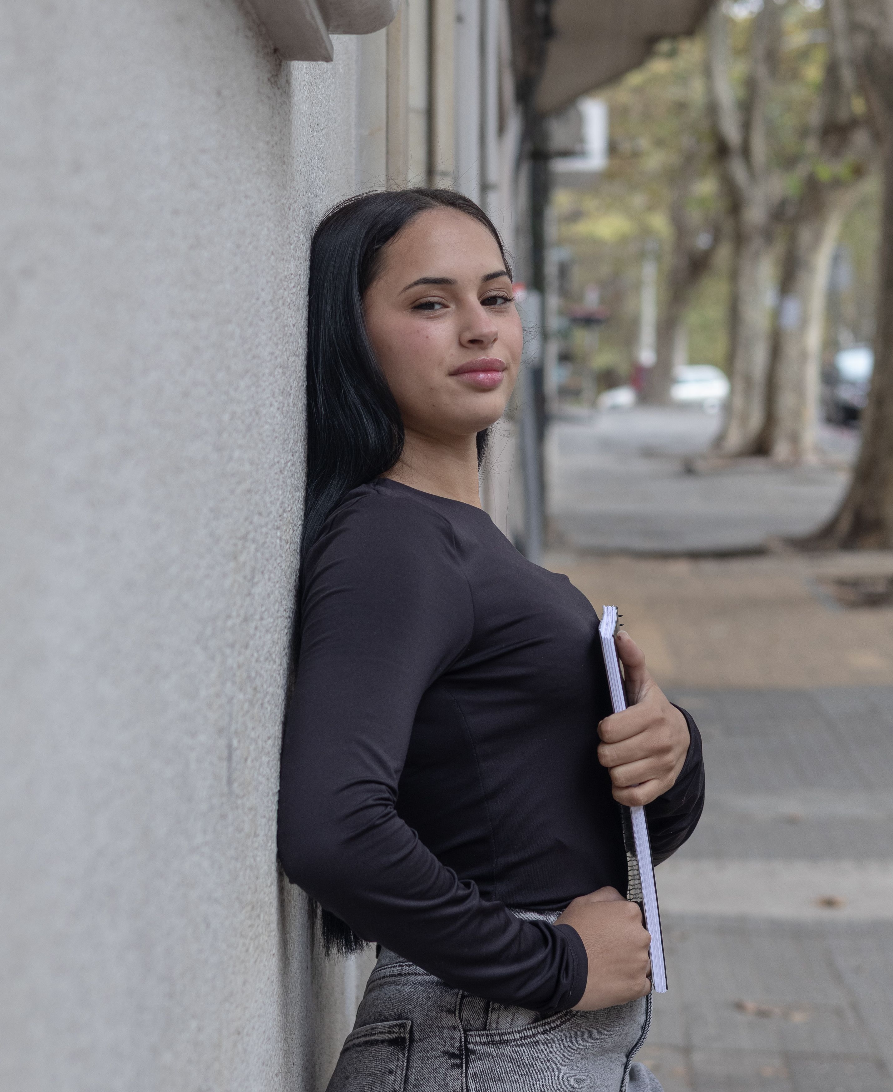 Portrait of a young woman leaning against a wall in Montevideo, Uruguay, exuding confidence.