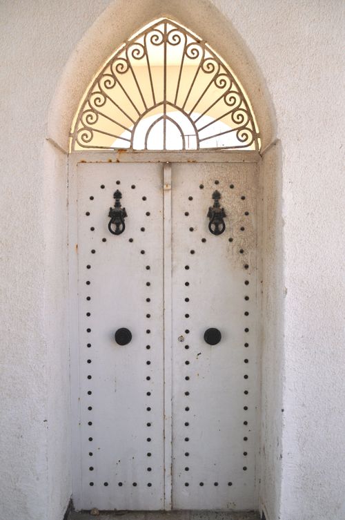 Free Explore this beautifully detailed Tunisian white door with intricate ironwork in Tunis. Stock Photo
