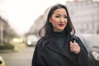 一位美丽的亚洲女性穿着时尚外套，站在城市街道上