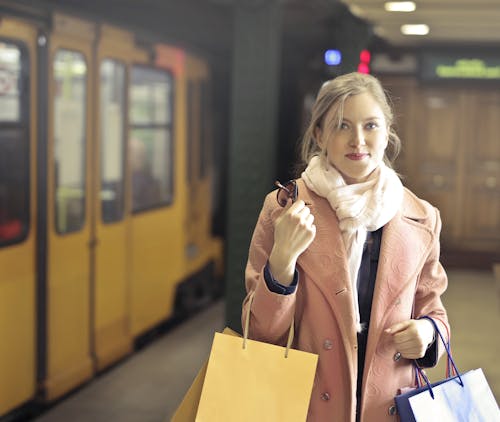 Mujer En Abrigo Rosa Sosteniendo Bolsas De La Compra.