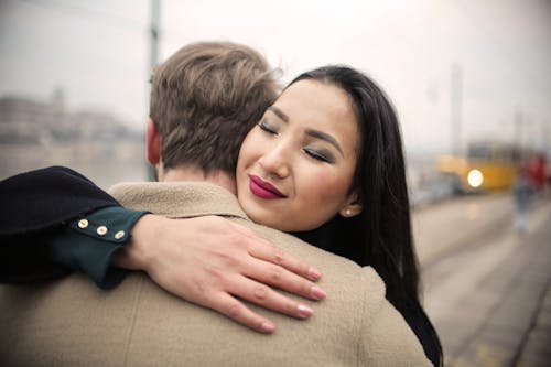 Woman in Black Coat Hugging Man in Brown Coat