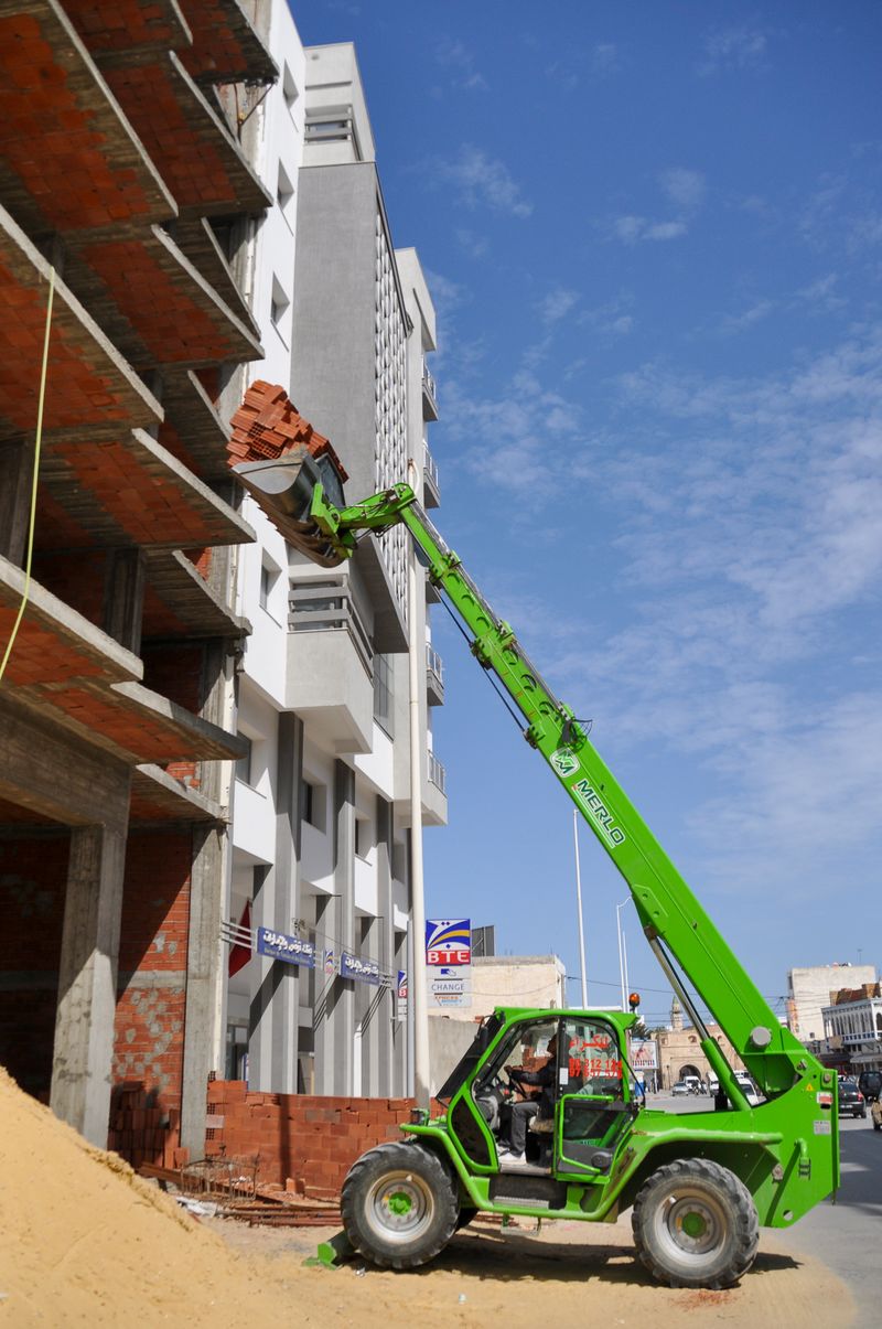 A telehandler lifting bricks at a construction site in Tunis, Tunisia