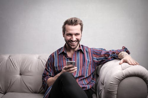 Free Man in Striped Long Sleeve Using Mobile Phones Stock Photo