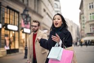 一对夫妇背着五颜六色的袋子，在繁华的城市街道上享受购物日