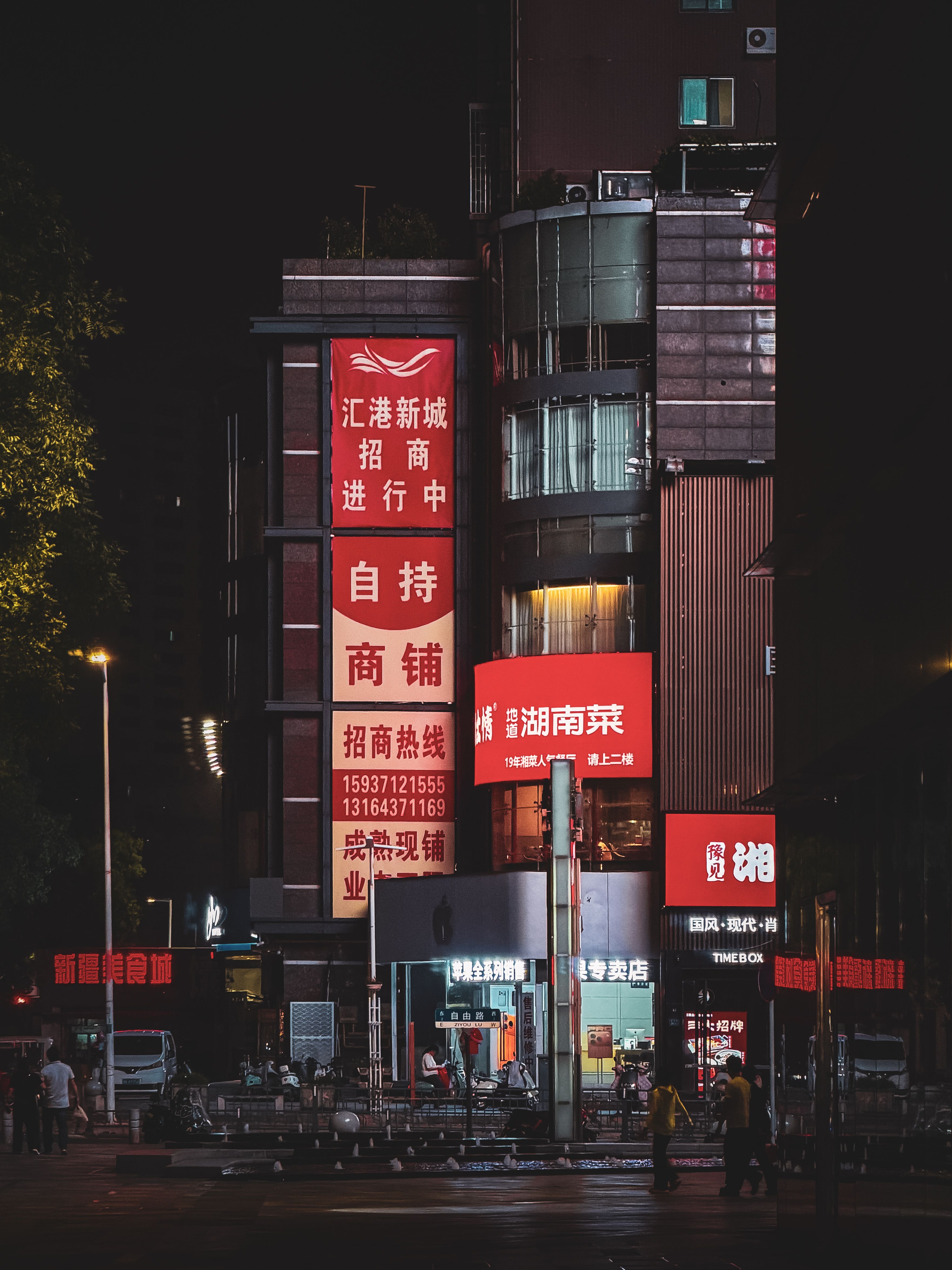 Bustling street in Zhengzhou at night with illuminated signage and urban architecture.