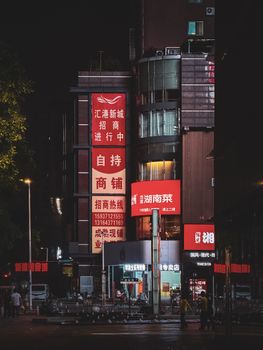Bustling street in Zhengzhou at night with illuminated signage and urban architecture.