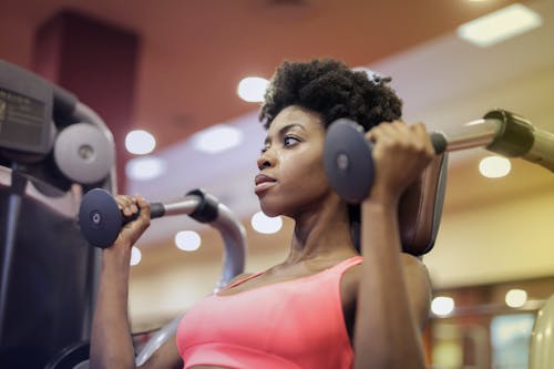 Wanita Dengan Bra Sport Pink Duduk Di Perlengkapan Latihan