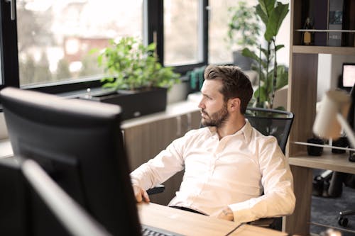 Man in White Shirt Sitting on Black  Chair