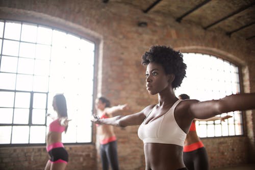 Free Confident fit ethnic woman training with other sportswomen in modern fitness studio Stock Photo