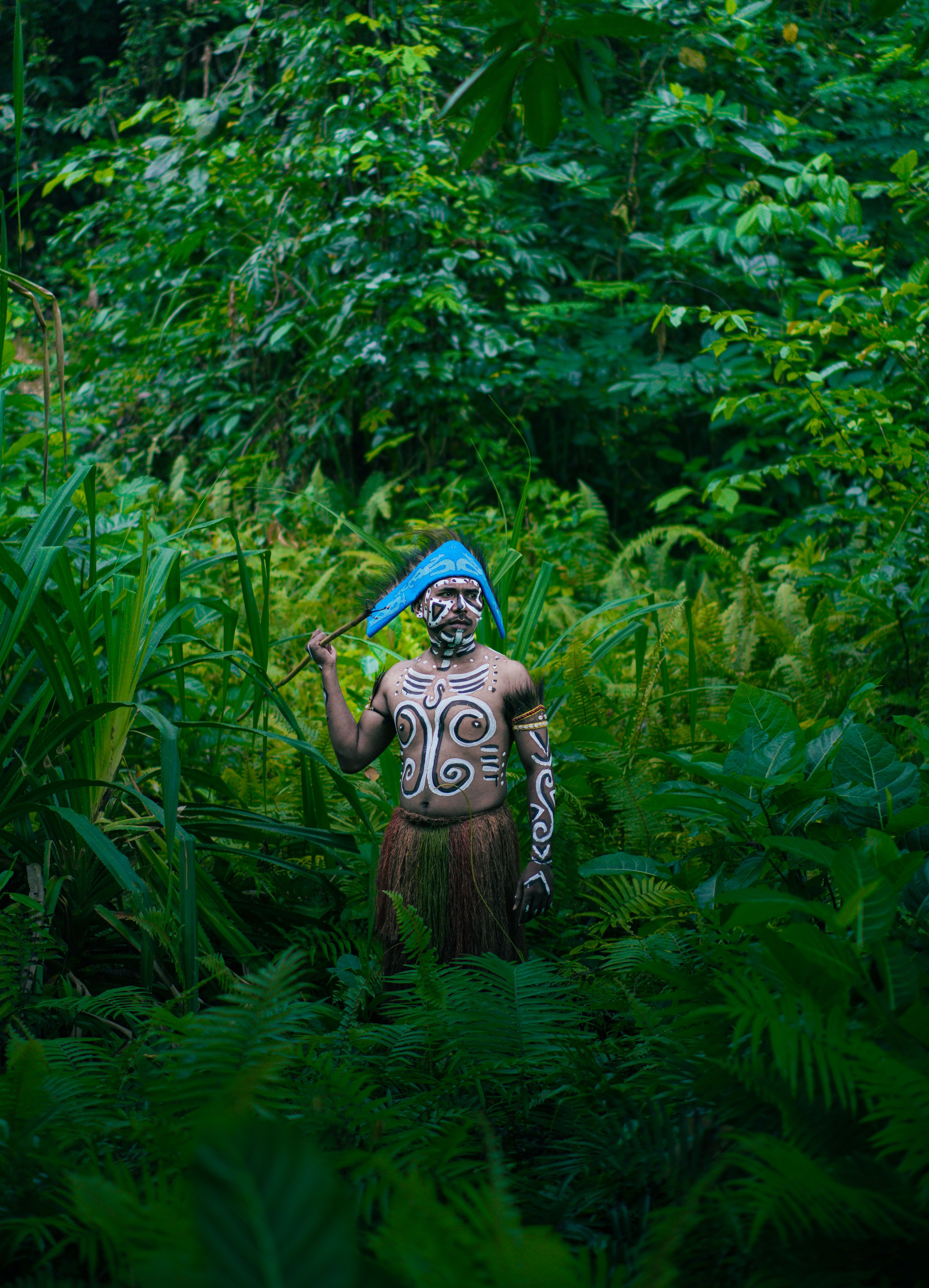 Indigenous person in traditional attire in lush jungle of Southwest Papua, Indonesia.
