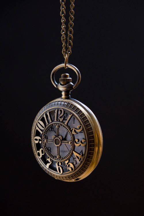 Free Classic vintage pocket watch against a dark background, highlighting its ornate details and chain. Stock Photo