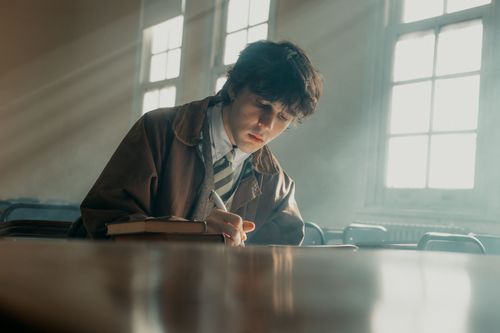 Free A young student writes attentively in a sunlit classroom in Buenos Aires. Stock Photo