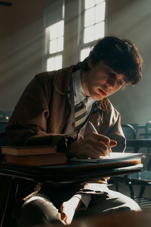 Free A young student writing in a sunlit classroom, focusing intently on their work. Stock Photo