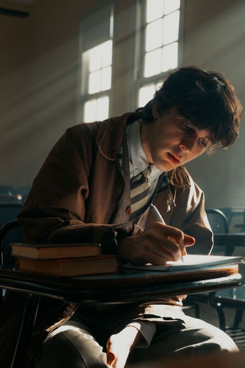 Free Young man intensely writing notes in a classroom, focused on study. Stock Photo