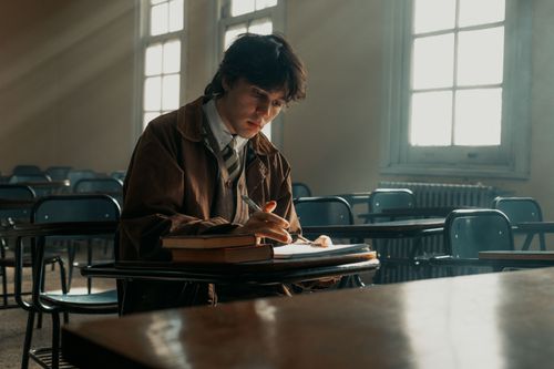 Free Student focused on studying in quiet Buenos Aires classroom, natural light streaming through windows. Stock Photo