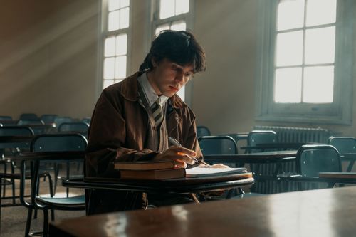 Free A focused university student studies alone in an empty classroom, bathed in daylight. Stock Photo
