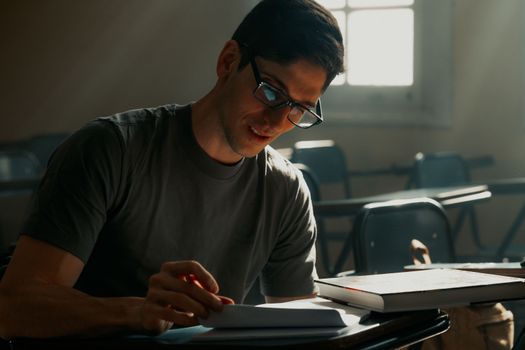 Young university student studying in a sunlit Buenos Aires classroom, focusing on notes.