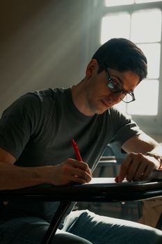 Young adult studying in a classroom with sunlight streaming in through the window, creating an inspiring atmosphere.