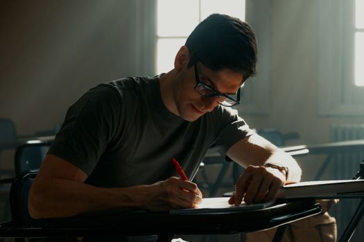 University student concentrating on notes in a sunlit Buenos Aires classroom.