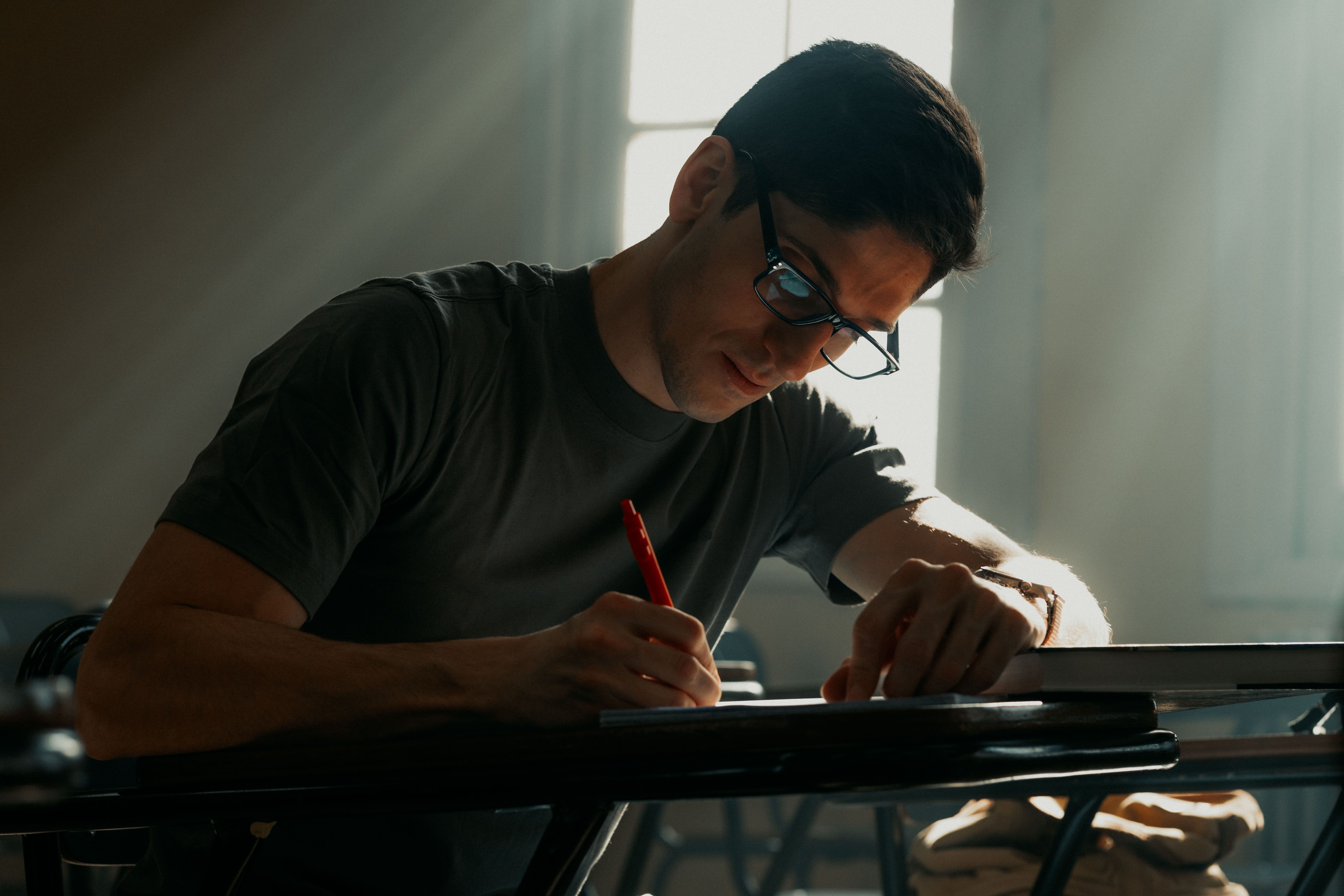 Focused student writing notes in natural light, Buenos Aires.