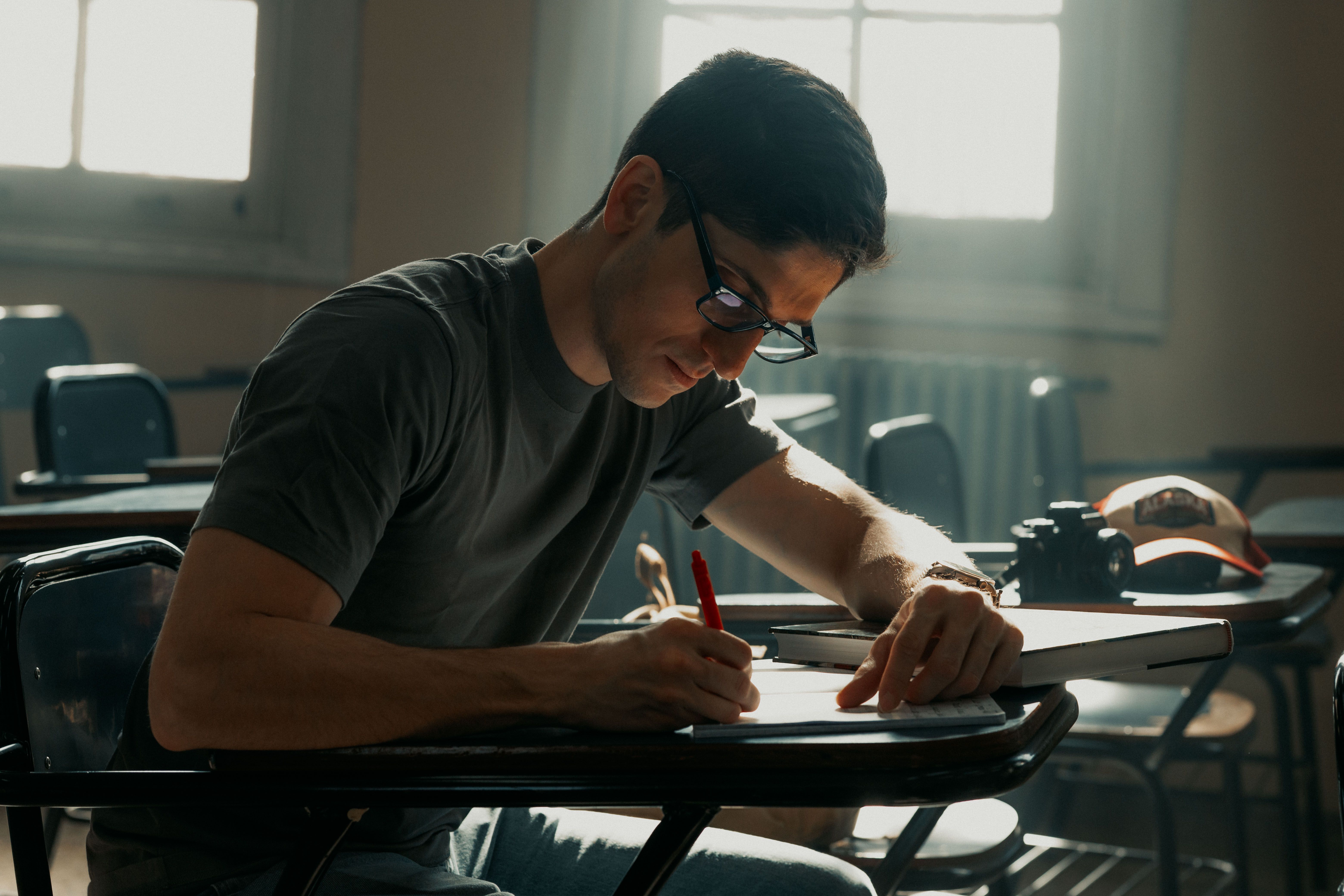 Man diligently studying in a university classroom setting during the day.