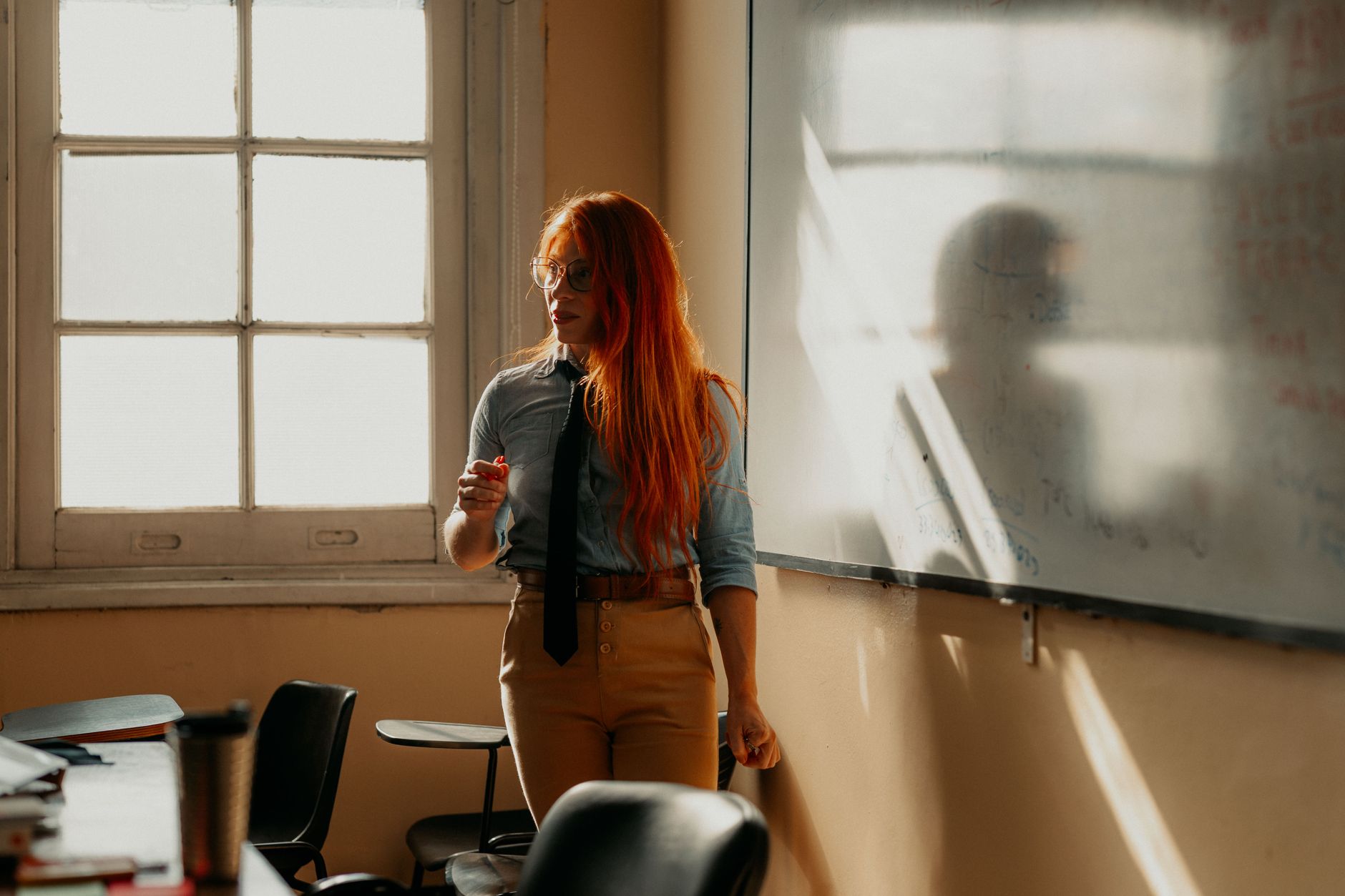 A student stands by a whiteboard in a sun-drenched classroom in Buenos Aires.