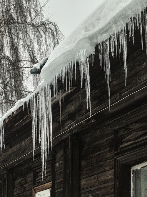 Free Captivating icicles hanging from a rustic snowy roof, showcasing winter's chill and beauty. Stock Photo